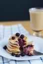 Eating of slapjack or oladyi with black raspberry with fork on white plate and cocoa Royalty Free Stock Photo