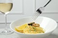 Eating tasty capellini with mussels and lemon at light grey table, closeup. Exquisite presentation of pasta dish