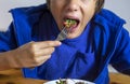 eats vegetable salad with a fork, mouth open wide.. Royalty Free Stock Photo