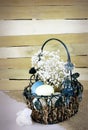 Eatser image includes a green, wire basket with colorful spotted eggs and baby`s breath on a rustic wooden background.