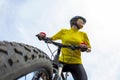 Eautiful girl cyclist in yellow looking forward, holding the bike. Sports and recreation