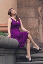 Eautiful woman in purple dress sitting on the steps Royalty Free Stock Photo