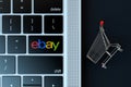 Ebay logo on laptop keyboard and miniature shopping cart. 3D Rendering