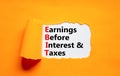 EBIT symbol. Concept words EBIT earnings before interest and taxes on white paper on beautiful orange background. Business EBIT