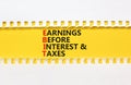 EBIT symbol. Concept words EBIT earnings before interest and taxes on yellow paper on beautiful white background. Business EBIT