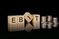 EBIT - text on wooden cubes on dark backround with coins. business concept