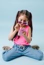 Eccentric dressed up tween girl in pink shirt and round sunglasses using phone Royalty Free Stock Photo