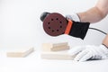 Eccentric grinding machine in hands. Power tool. On a white. The master of wood blocks in gloves grinds Royalty Free Stock Photo