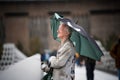Eccentric man stood on bridge large broken umbrella up in rain London city centre eyes closed enjoying fresh air