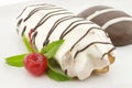 Eclair and biscuit with chocolate icing and mint, on white background. Selective focus Royalty Free Stock Photo