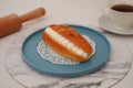 Eclair on a blue plate with marble table Royalty Free Stock Photo