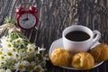 Eclair, coffee cup, alarm clock and charmomile. Royalty Free Stock Photo