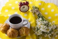 Eclair, coffee cup, alarm clock and charmomile. Royalty Free Stock Photo