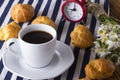 Eclair, coffee cup, alarm clock and charmomile. Royalty Free Stock Photo