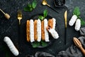 Eclair with cream. Creamy dessert on a black stone plate. Top view. Rustic style