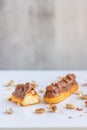 Eclair with vanilla cream, peanuts and chocolate. Royalty Free Stock Photo