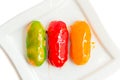 Eclairs with colorful caramel glaze on white plate