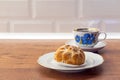 Eclairs with custard and on a white plate. Eclairs with cream filling covered with powdered sugar and cup of black tea with