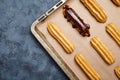 Eclairs or profiterole with chocolate preparing on baking sheet