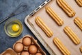 Eclairs or profiterole preparing with eggs on baking sheet background