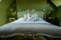 Eclectic bedroom with French Rococo style bed, and walls painted in deep green colour.
