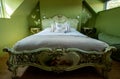 Eclectic bedroom with French Rococo style bed, and walls painted in deep green colour.