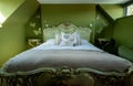 Eclectic bedroom with French Rococo style bed, and walls painted in deep green colour.