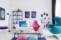 Eclectic living room with blue egg chair, metal coffee table and white couch with colorful pillows, real photo with copy space