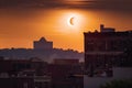 the eclipse, with the moon in front of the sun, and a view of silhouette buildings in the background