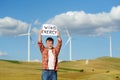 Eco activist with banner `Wind Energy` on background of power stations for renewable electric energy production.