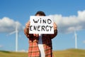 Eco activist with banner `Wind Energy` on background of power stations for renewable electric energy production.
