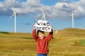 Eco activist boy with banner `Wind Energy` on background of power stations for renewable electric energy production