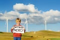 Eco activist boy with banner Wind Energy on background of power stations for renewable electric energy production.