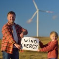 Eco activists with banner `Wind Energy` on background of power stations for renewable electric energy production. Royalty Free Stock Photo