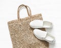 Eco bag made of straw, sport white snickers shoes on a white background, top view. Shopping walking concept