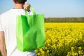 Eco bag. Man holding an eco bag on background of rapeseed field. Layout for design Royalty Free Stock Photo