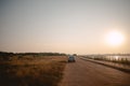 Eco car parking on side country road of rural grass field with sunset and river. Royalty Free Stock Photo