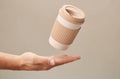 Eco Coffee Cup above Hand on Beige Background