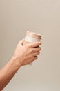 Eco Coffee Cup in Hand on Beige Background