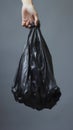 Eco-conscious Waste Disposal: Holding Black Trash Bag.