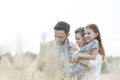 Smiling parents carrying daughter amidst wheat crops at farm