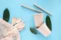 Eco-friendly biodegradable disposable cup and spoon, forks, knives, bamboo tubes, cotton string bag and dishwashing brush on a Royalty Free Stock Photo