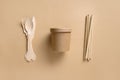 Eco-friendly biodegradable disposable cups and individual spoons, forks, bamboo straws on beige