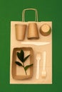 Eco-friendly disposable bamboo utensils wood and paper on green background