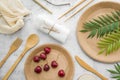Eco friendly disposable dishes made paper and bamboo on white marble background. Draped spoons, fork, knives, plate with