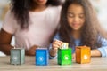 Eco-friendly family activities. Lovely little black girl with her mother playing garbage sorting board game at home Royalty Free Stock Photo