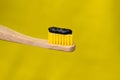 Eco friendly natural bamboo toothbrush with black charcoal whitening toothpaste isolated on yellow background Royalty Free Stock Photo