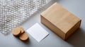 Eco-friendly packaging setup with brown cardboard box, bubble wrap, cork coasters, and blank white card on gray surface for Royalty Free Stock Photo