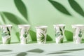 Eco friendly paper cups with green leaf pattern on mint background Royalty Free Stock Photo