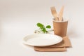 Eco friendly paper dishes, napkins. White plate, craft cup, wooden cutlery: fork, knife. Still life with cherry flowers. Recyclabl